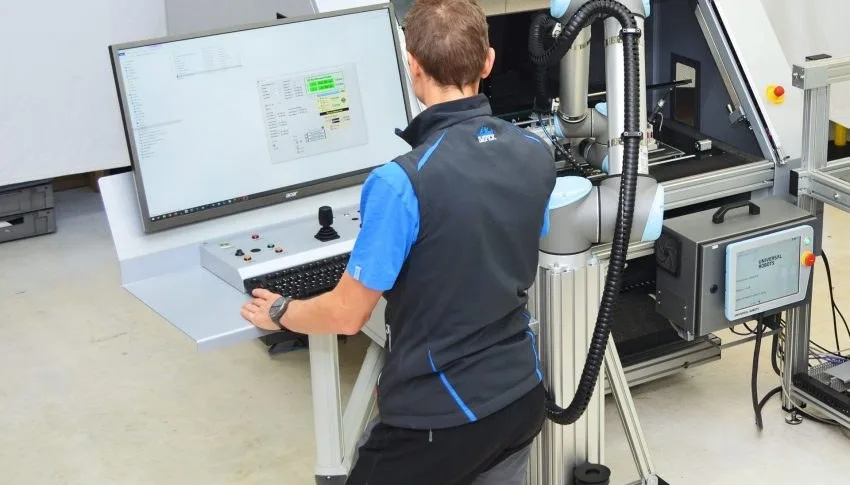 Mitarbeiter am Bedienpult einer Messmaschine mit Roboterarm