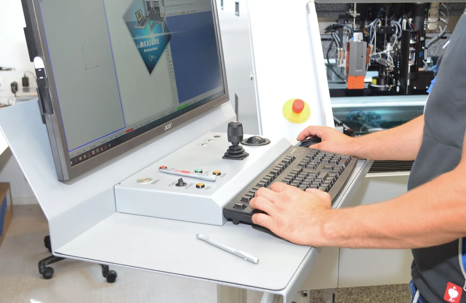Hände an Tastatur und Joystick am Bedienpult einer Messmaschine